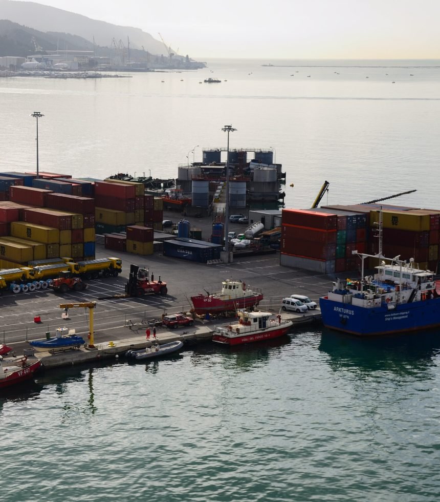 ships with many containers and vehicles at the port